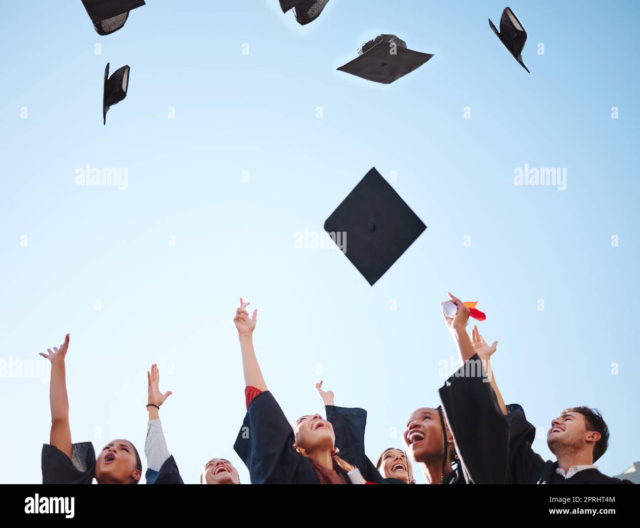 Abschlussfeier, Studenten und Graduiertenklasse werfen bei der Zeremonie Kappen in die Luft und freuen sich über den Bildungserfolg. Universität oder Hochschule Männer und Frauen d Stockfoto