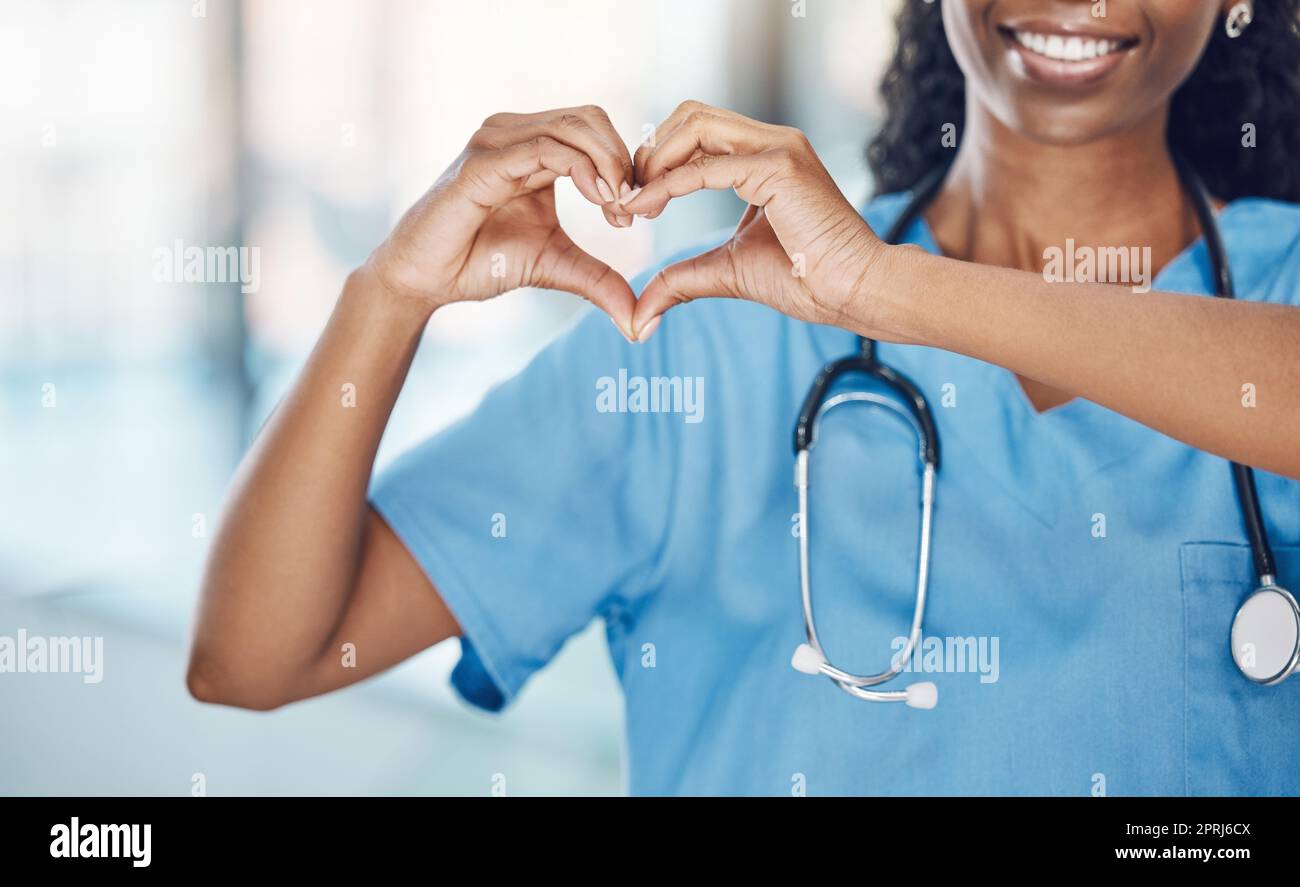 Herzhand und schwarze Krankenschwester im Krankenhaus mit Ausdruck, um Liebe und Fürsorge für die Karriere zu zeigen. Professioneller Sanitäter in Uniform mit ha Stockfoto