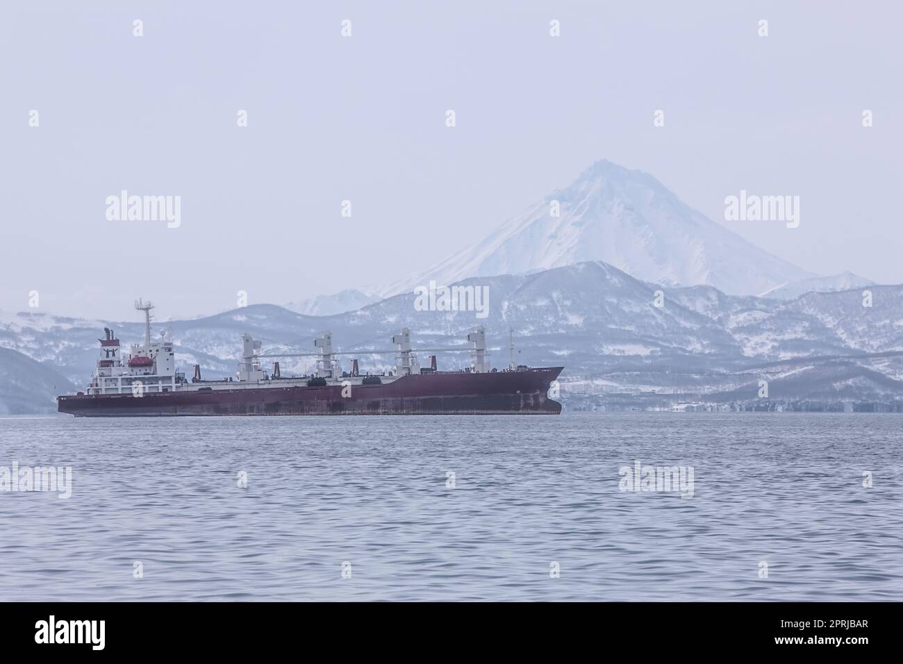 Kamtschatka Halbinsel, Russland. Seehafen in Petropavlovsk-Kamtschatsky. Schiffe im Straßenstead vor dem Hintergrund des Vulkans Stockfoto