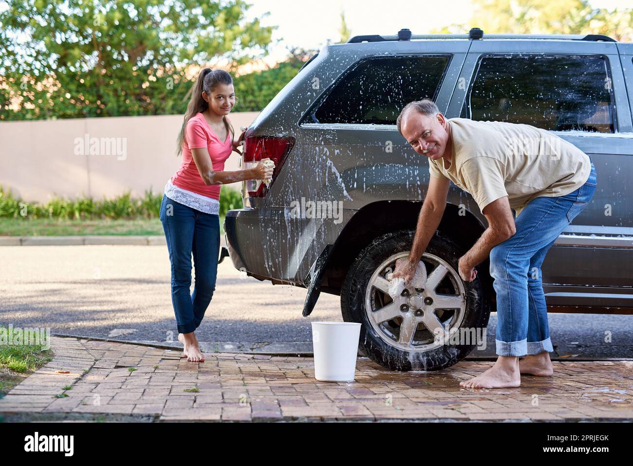 Das ist ihre gemeinsame Zeit. Porträt eines Vaters und einer Tochter, die draußen ein Auto waschen. Stockfoto