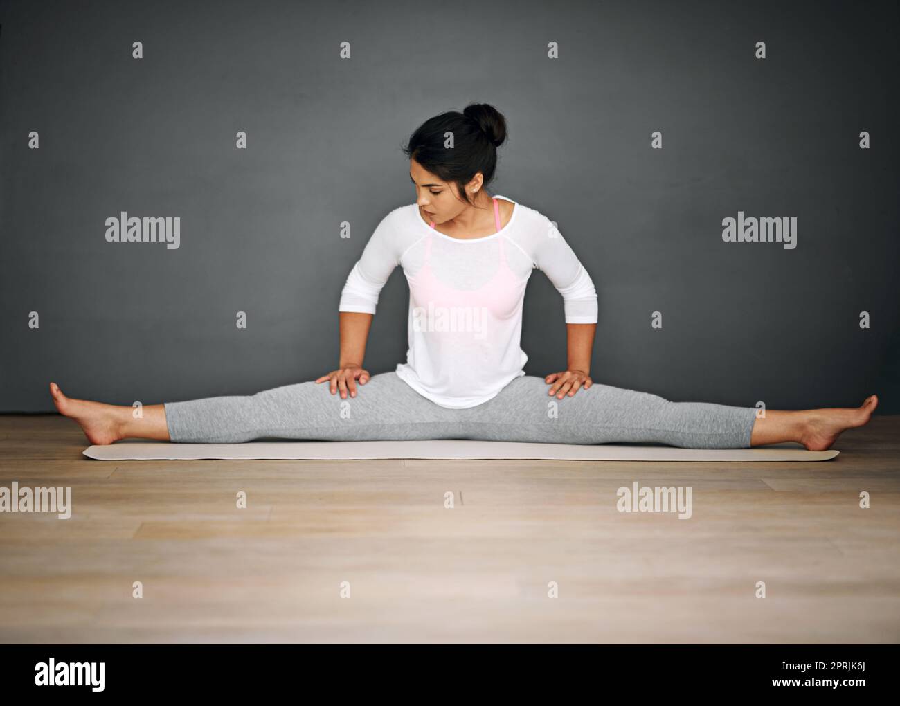 Geben Sie ihren Hamstrings ein gutes Training. Eine attraktive junge Frau, die die Splits in ihrer Yoga-Routine macht. Stockfoto