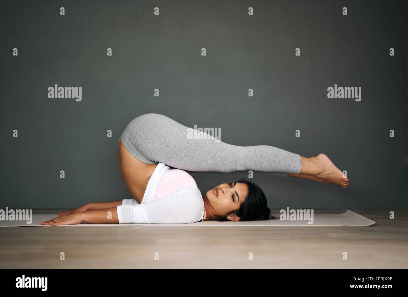 Das letzte Mal, als du deine Knie aus nächster Nähe gesehen hast, wird es wehend. Porträt einer flexiblen jungen Frau, die Yoga macht. Stockfoto