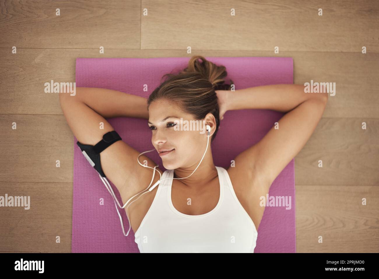 Tun Sie, was Sie glücklich macht. Aufnahme einer jungen Frau, die Musik hört, während sie auf ihrer Yogamatte liegt. Stockfoto