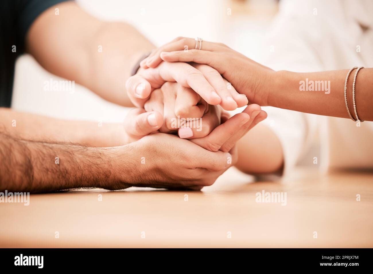Unterstützung, Fürsorge und Familie halten sich am Tisch die Hände zusammen, um Einfühlungsvermögen, Liebe und Hoffnung zu zeigen. Nahaufnahme von Verbindung, Vertrauen und Freundschaft in der kommunalen Reha-Gruppe zeigt Mitgefühl und Dankbarkeit. Stockfoto
