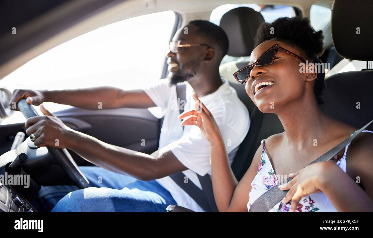 Freiheit, Reisen und ein glückliches Paar auf einer Autofahrt, das Musik singt und Auto fährt. Schwarze Frau und Mann aus Kenia entspannen sich auf Reisen in einem Sommerurlaub oder in einem mobilen Transport mit einem Lächeln Stockfoto