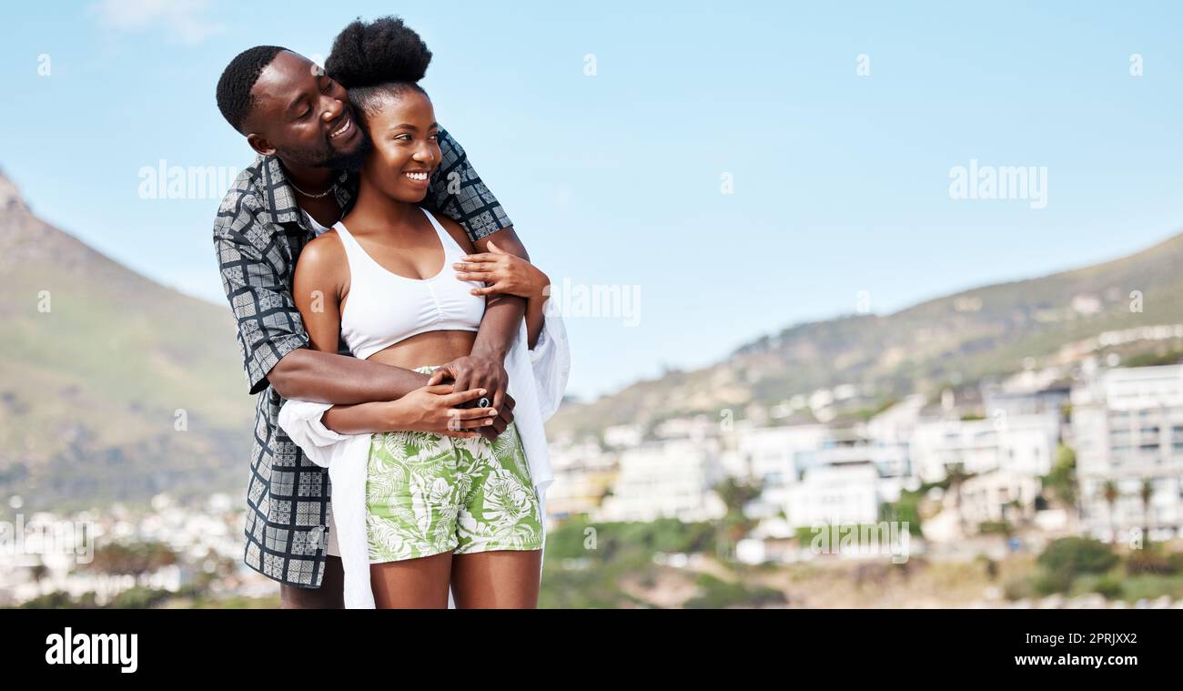 Frohes afrikanisches Urlaubspaar, Lächeln und lieben Umarmung in der Natur Sommersonne mit Musterraum. Glück von Menschen mit einer entspannten, friedlichen und ruhigen Urlaubseinstellung in der Sonne und klarem Himmel mit Modell Stockfoto