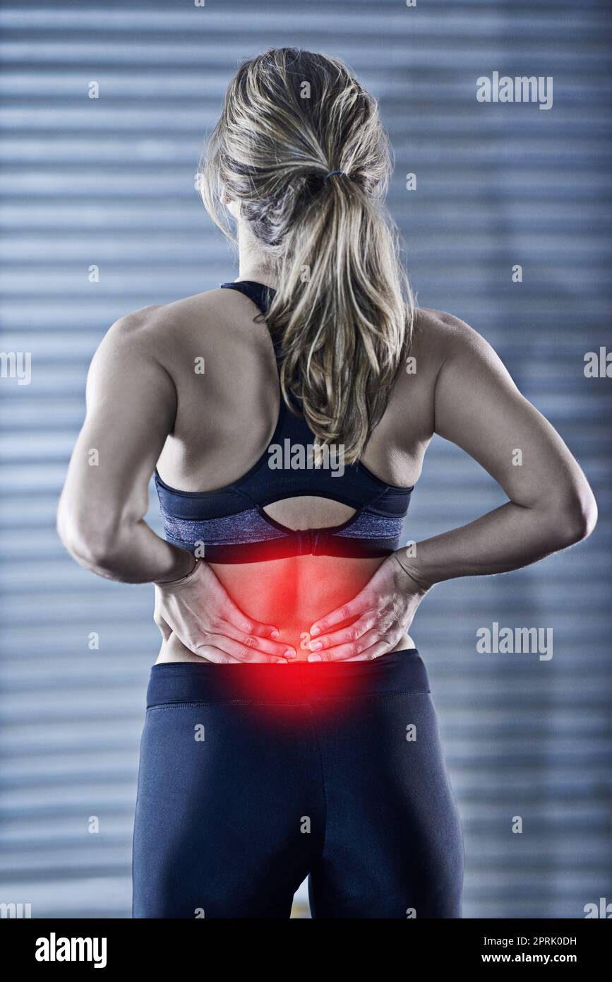 Wenn es nicht weh tut, funktioniert es nicht. Rückfahraufnahme einer jungen Frau, die ihren verletzten Rücken in rot markiert hält. Stockfoto