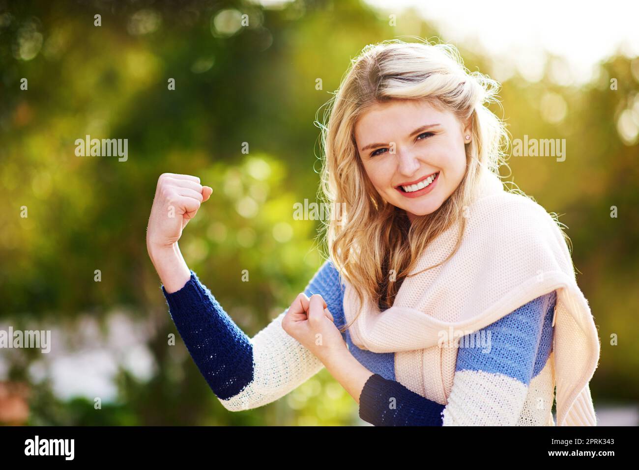 Willkommen bei der Waffenschau. Beschnittenes Porträt einer jungen Frau, die ihren Bizeps im Freien beutet. Stockfoto