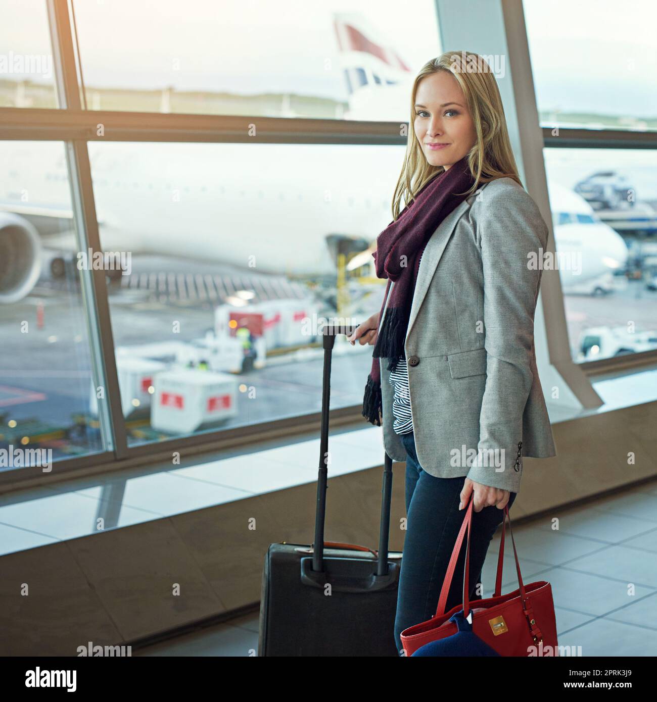 Shes, die in einem Düsenflugzeug abfliegen. Porträt einer jungen Frau, die mit ihrem Gepäck auf einem Flughafen steht. Stockfoto