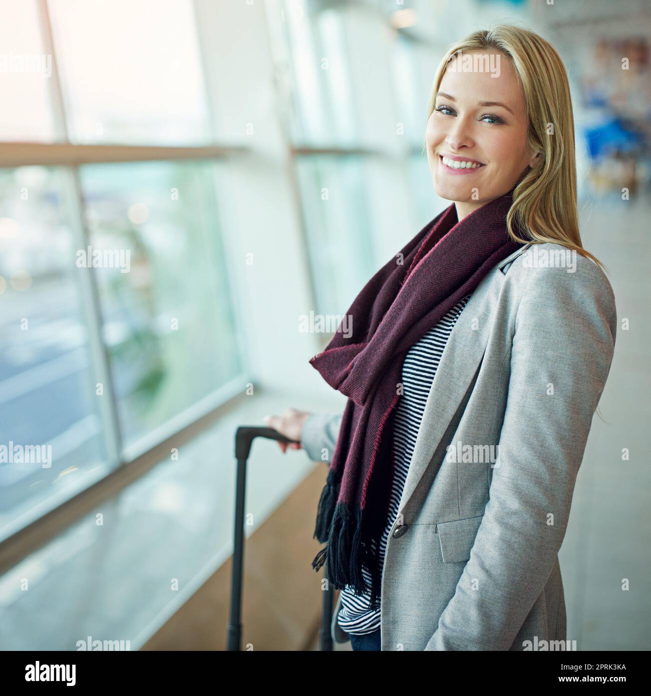 Warten auf Abflug. Porträt einer jungen Frau, die mit ihrem Gepäck auf einem Flughafen steht. Stockfoto