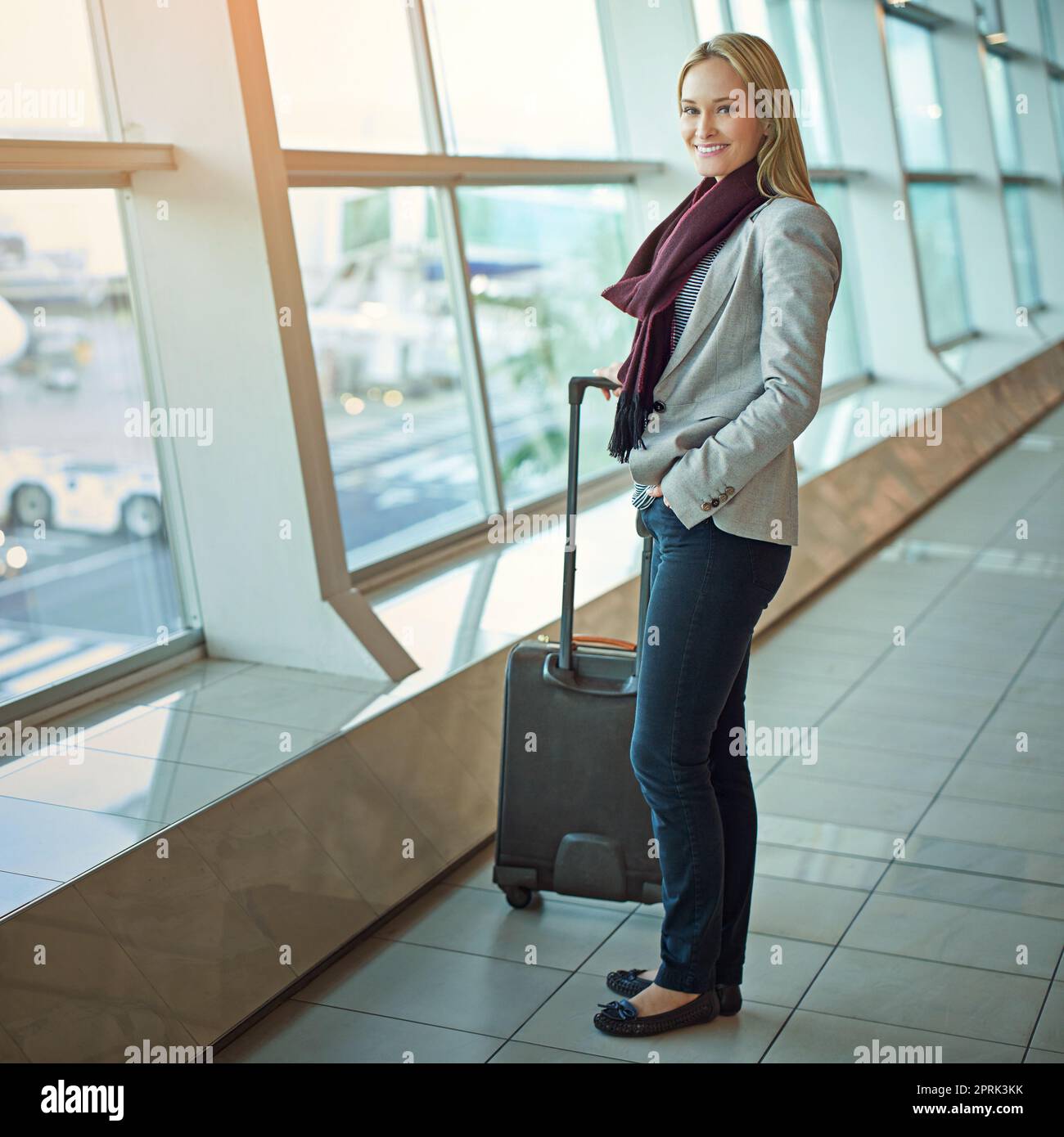Fliegen wir. Porträt einer jungen Frau, die mit ihrem Gepäck auf einem Flughafen steht. Stockfoto