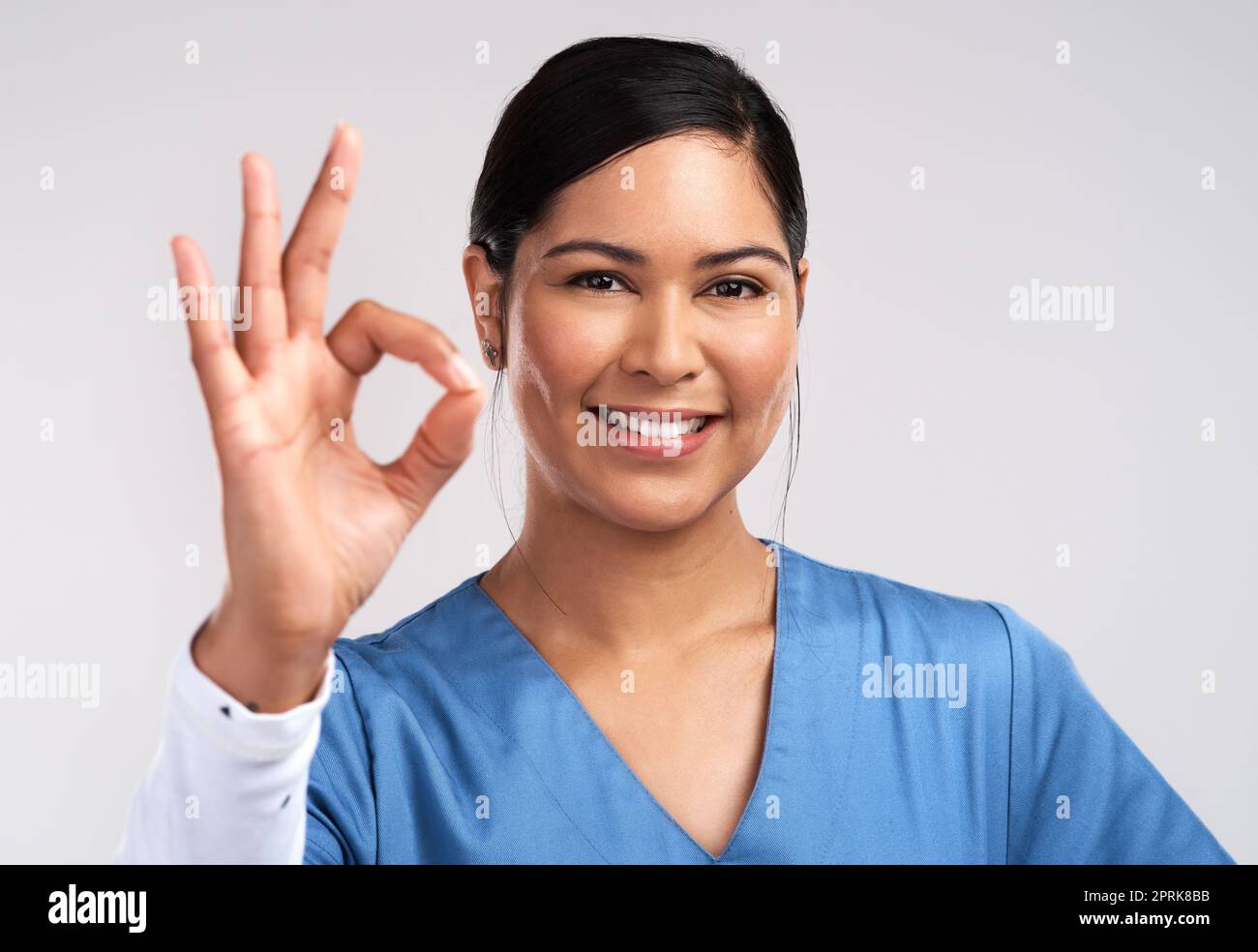 Ich bin ein Krieg zwischen Kopf und Herz. Porträt eines jungen Arztes mit dem OK-Zeichen vor weißem Hintergrund Stockfoto