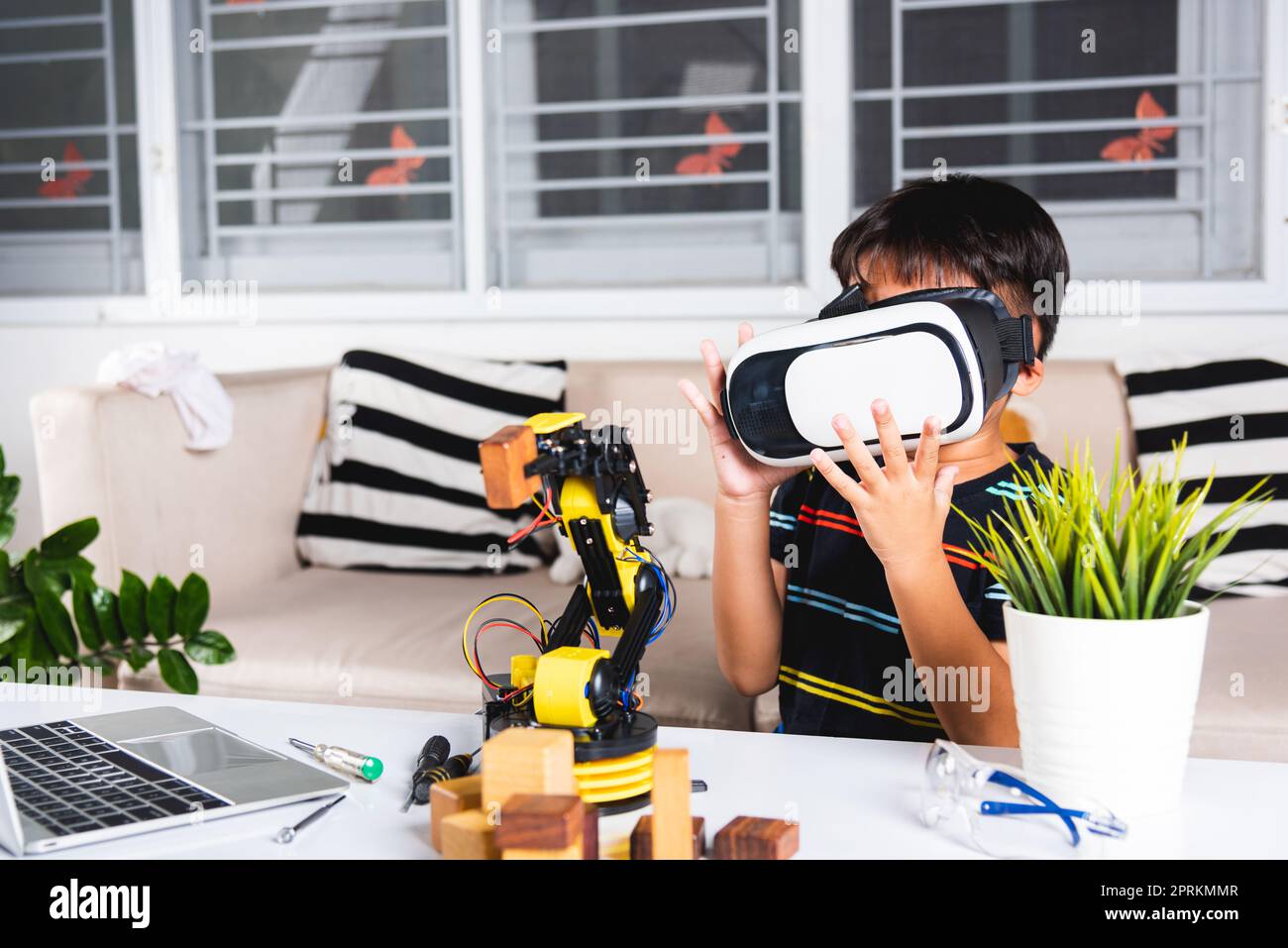 Asiatische Kind Junge mit VR-Brille auf Roboterarm in der Werkstatt, Kind lernen Programmer steuern Roboterarm mit Sensoren zu Holz Block, Technologie e Stockfoto