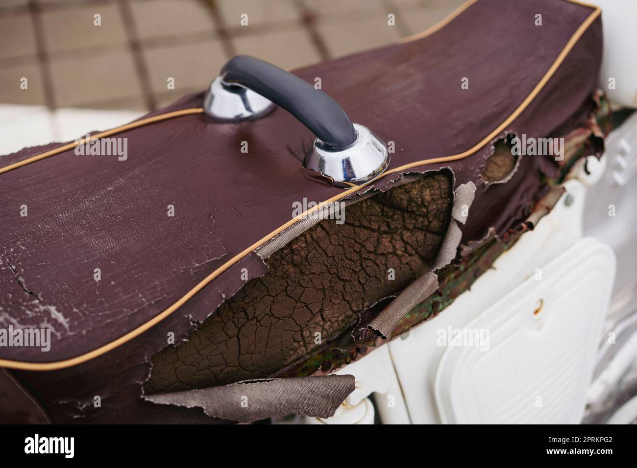 Brauner Motorrad-Sattelbezug aus Kunstleder (PVC oder PU), gerissen, um den Schwamm im Inneren zu sehen. Stockfoto