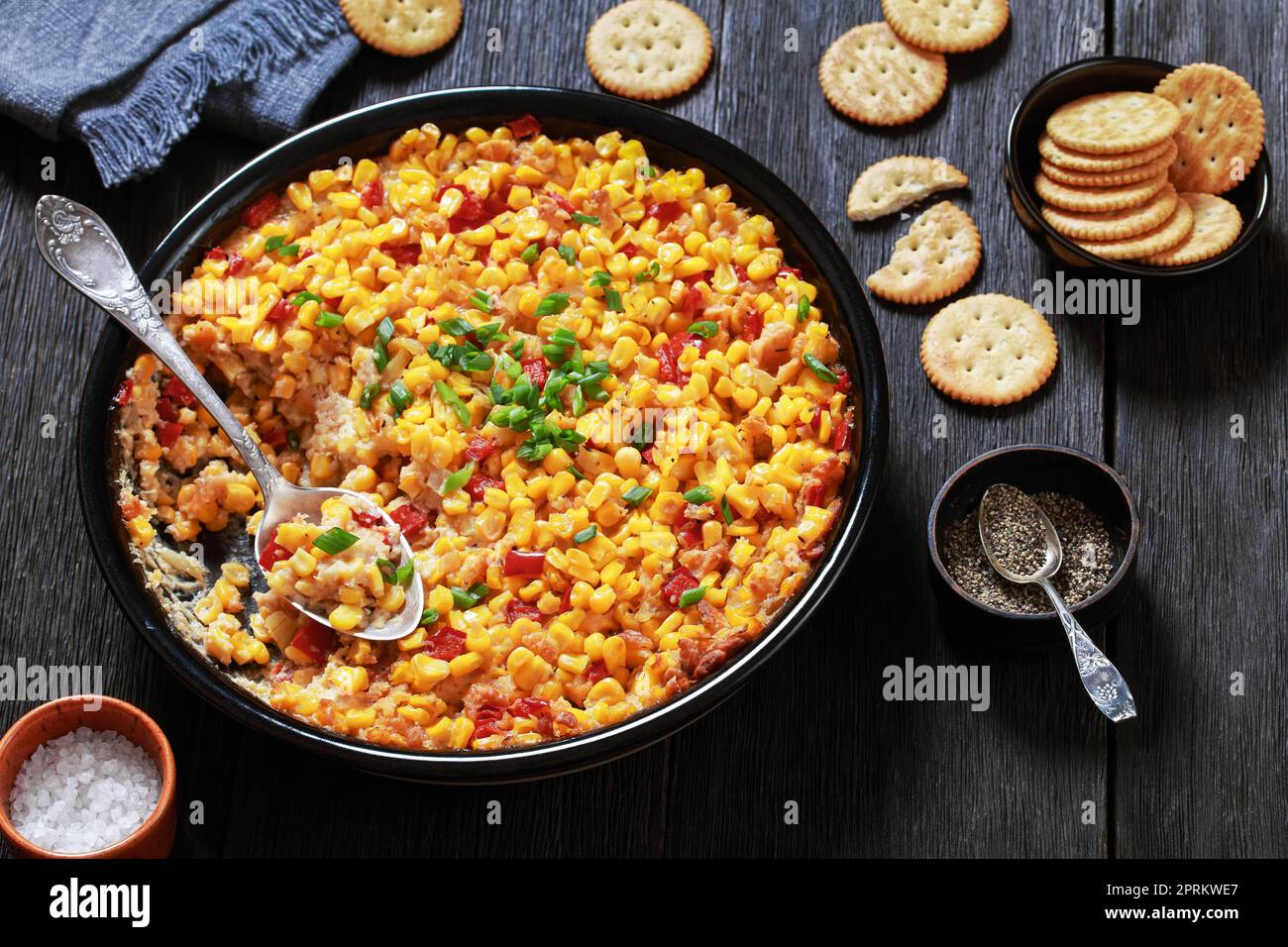 Maisauflauf im New Orleans Stil mit süßem roten Pfeffer, Butter, Crackern und Eiern in Backform auf dunklem Holztisch, amerikanisches Rezept Stockfoto