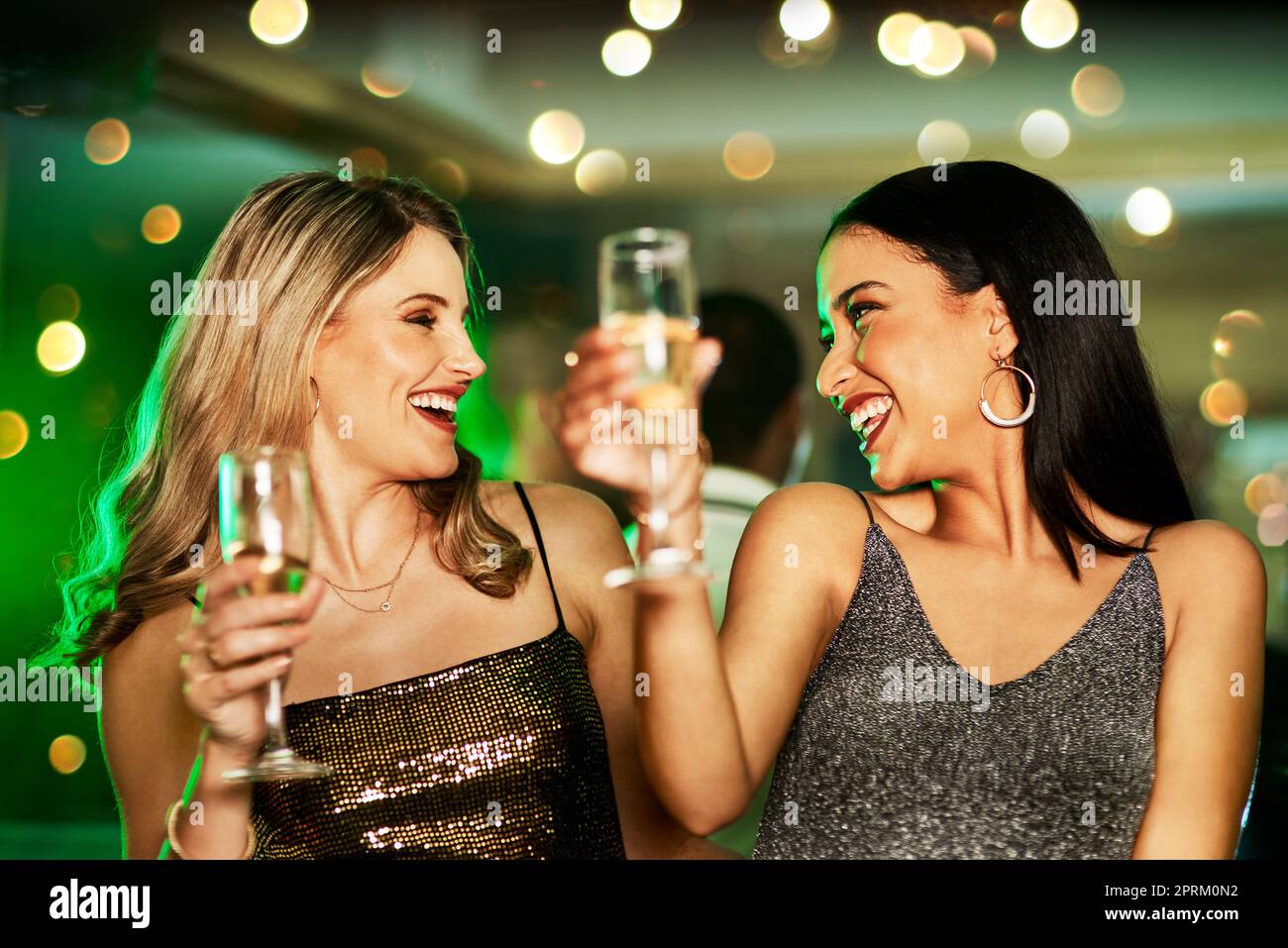 Sie wissen, wie man Spaß hat. Zwei fröhliche junge Frauen, die abends auf der Tanzfläche eines Clubs tanzen und einen Drink trinken Stockfoto