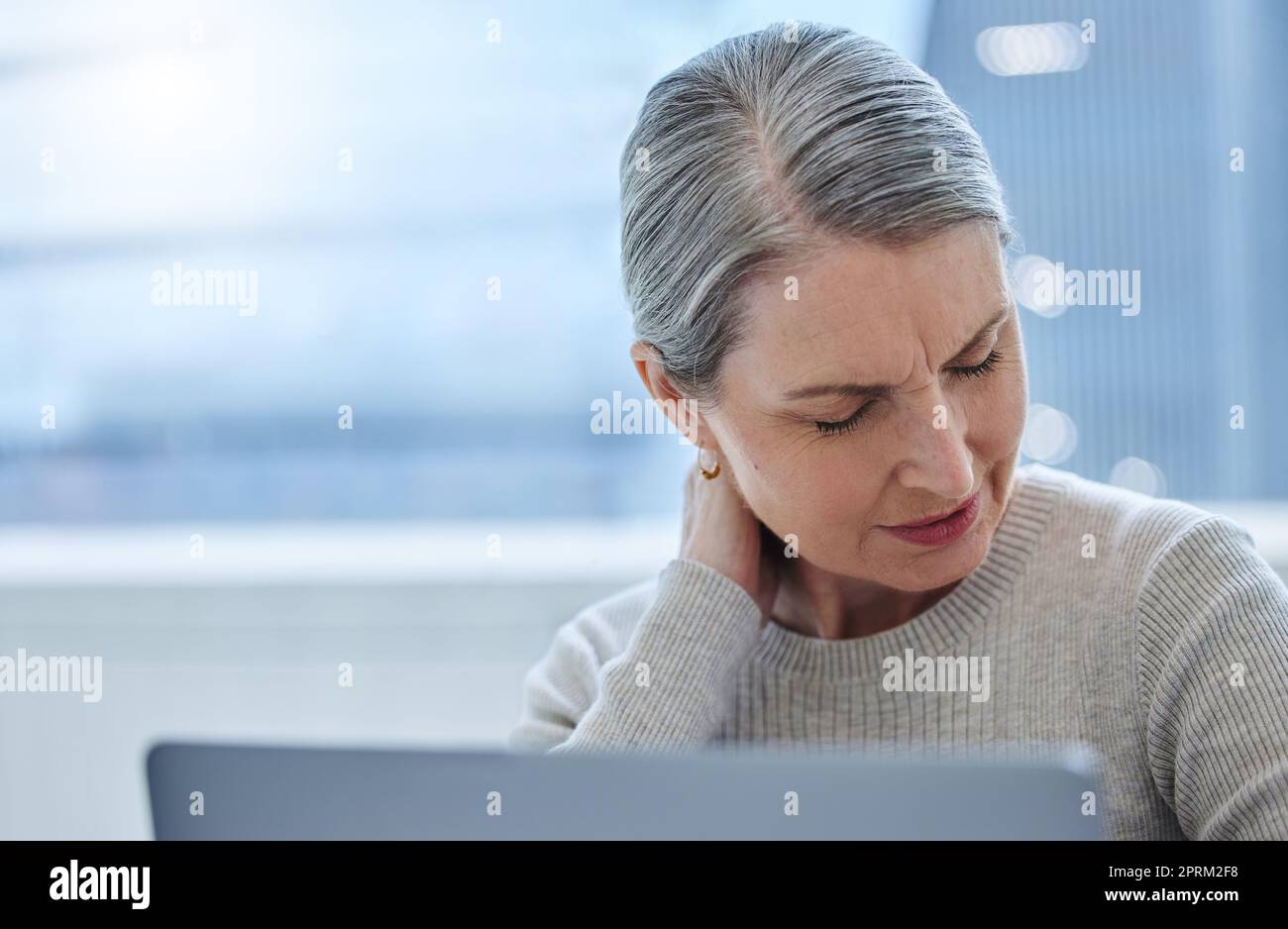 Ich werde zu alt für diesen Job. Eine reife Geschäftsfrau, die allein im Büro sitzt und Halsschmerzen hat Stockfoto