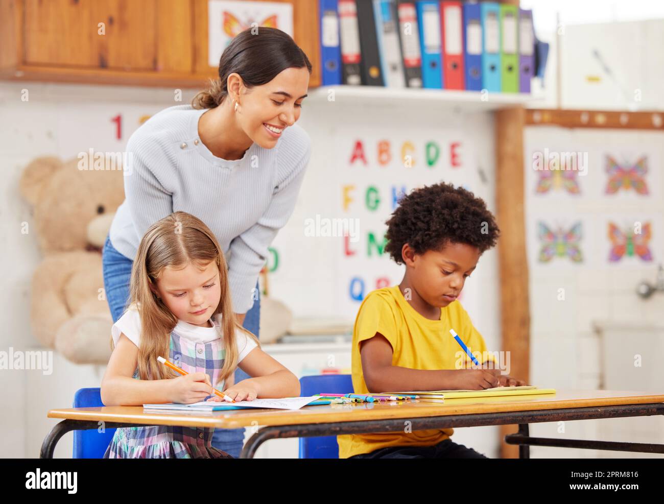 Die Farbgebung ist der perfekte Zeitpunkt, um das Benennen der Farben zu üben. Eine junge Frau, die eine Klasse von Vorschulkindern unterrichtet Stockfoto