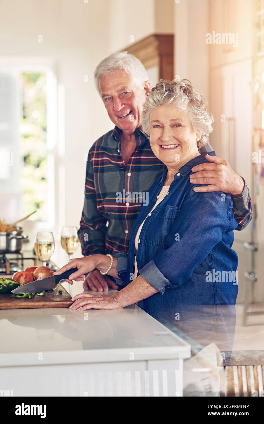 Ihre Küche ist mit Liebe gewürzt. Porträt eines älteren Ehepaares, das zu Hause in seiner Küche zusammen kocht. Stockfoto