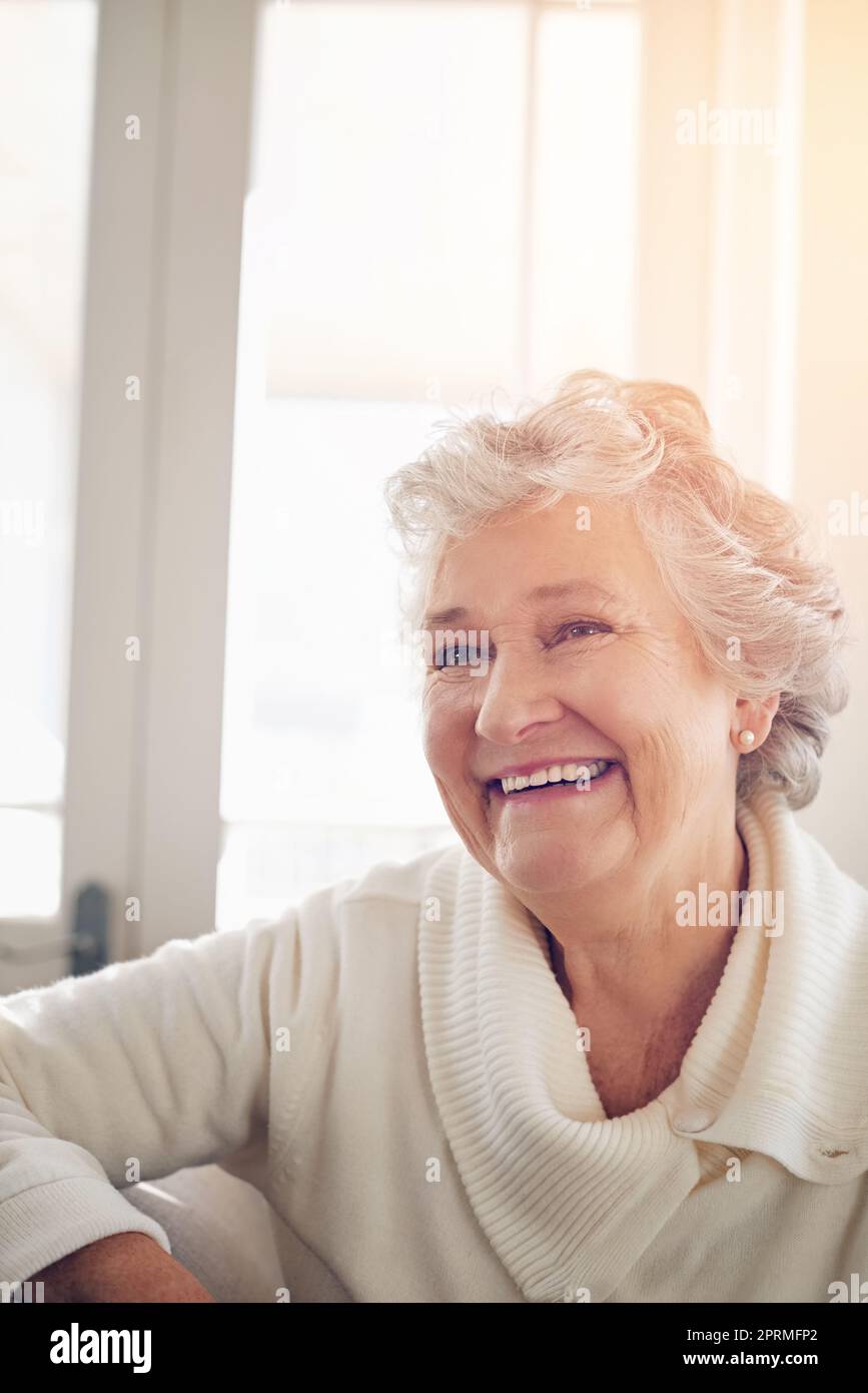 Ich hatte so viele wundervolle Erfahrungen, auf die ich zurückblicken konnte: Eine ältere Frau, die zu Hause nachdenklich aussschaute. Stockfoto