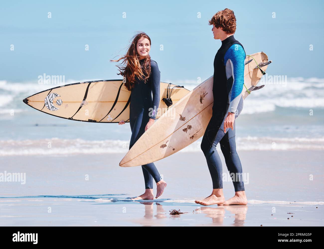Surfen, Surfen und spazierende Freunde oder Mann und Frau am Strand oder Sandsprecher. Surfbrett, Konversation und Menschen auf dem Meer für Sport oder Sport, Training und Training für einen Surferwettbewerb Stockfoto