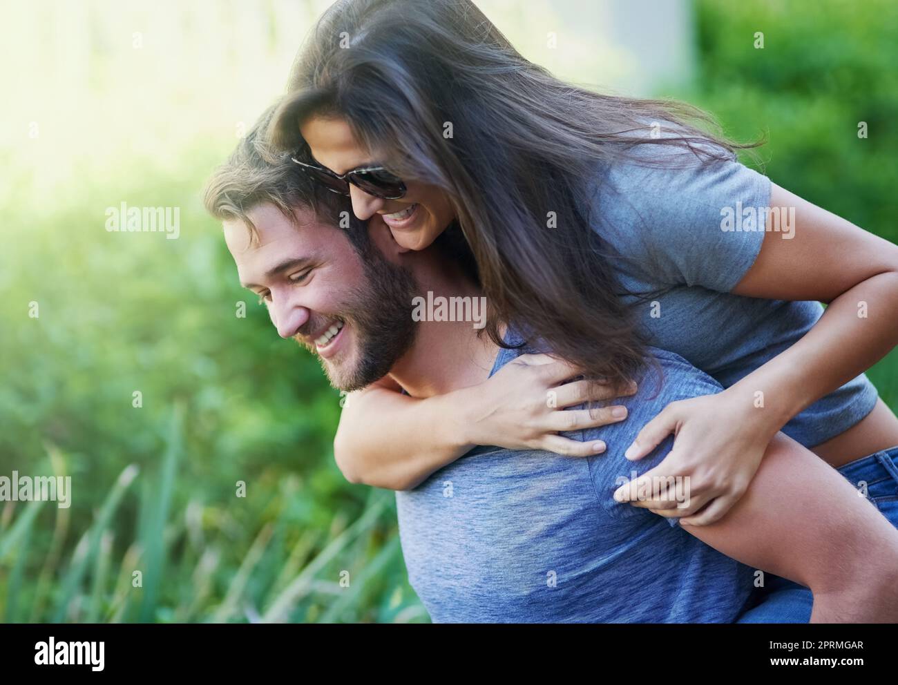 Sie finden immer Zeit, um Viel Spaß., einen jungen Mann, der seiner Freundin einen Huckepack gibt, während sie einen Tag draußen gemeinsam genießen. Stockfoto