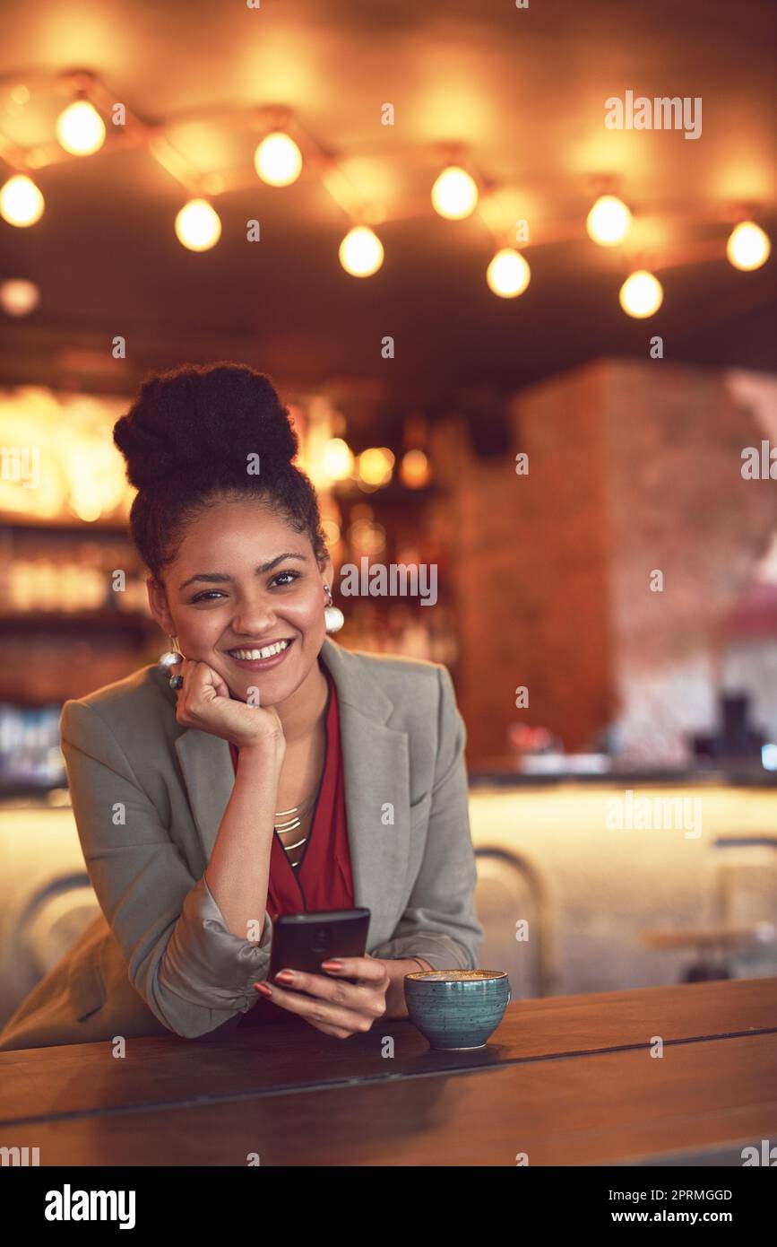 Ich komme hier wegen des schnellen und kostenlosen WiFi. Porträt einer jungen Geschäftsfrau, die in einem Café auf einem Handy schreibt. Stockfoto