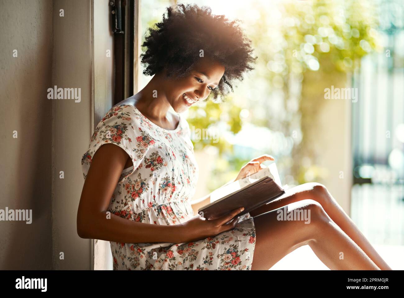 Gutes Buch und eine gemütliche Ecke. Eine junge Frau, die sich zu Hause mit einem Buch entspannt. Stockfoto