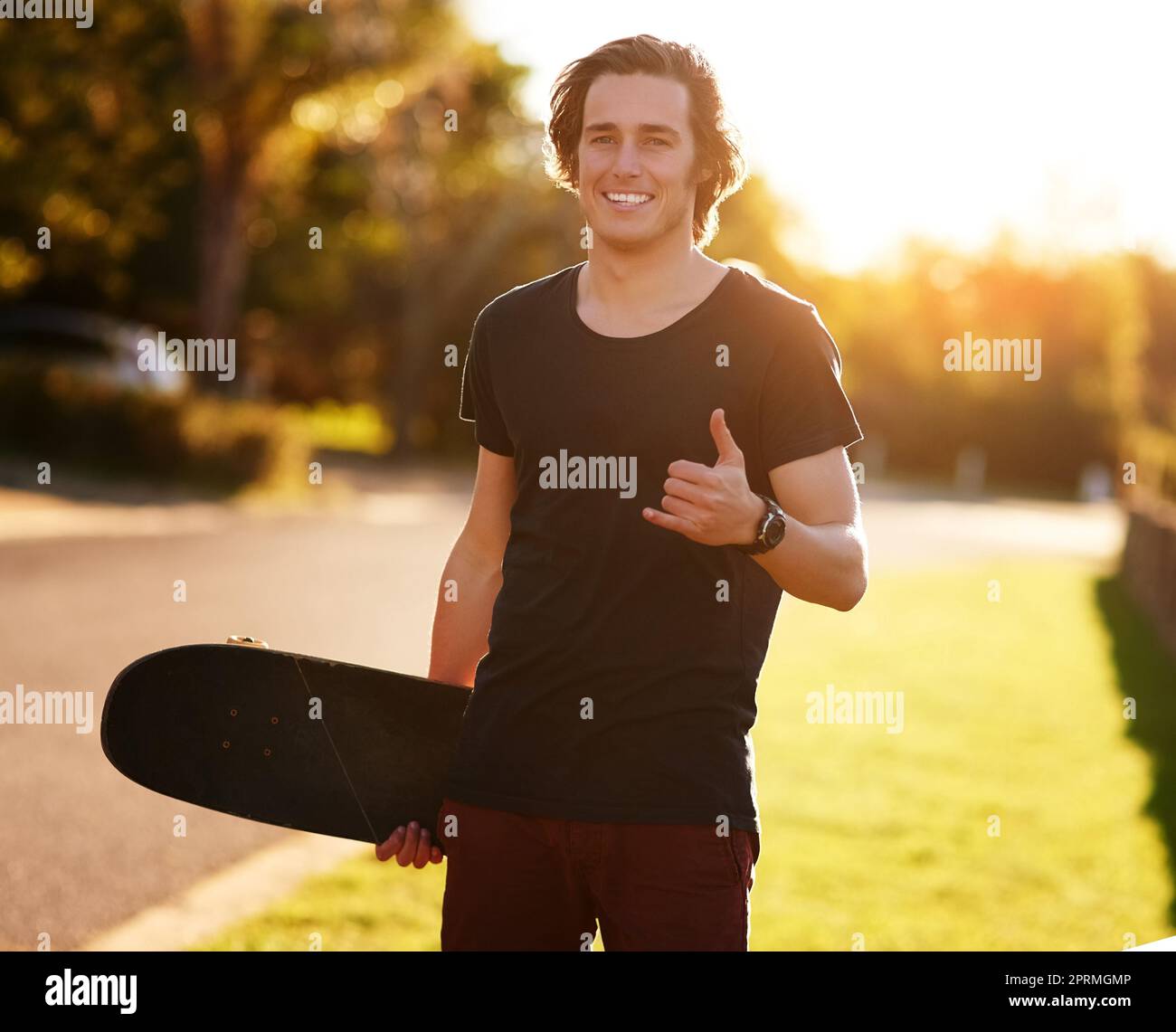 Ich könnte Euch einige Tricks beibringen. Porträt eines jungen Mannes, der mit seinem Skateboard draußen steht. Stockfoto