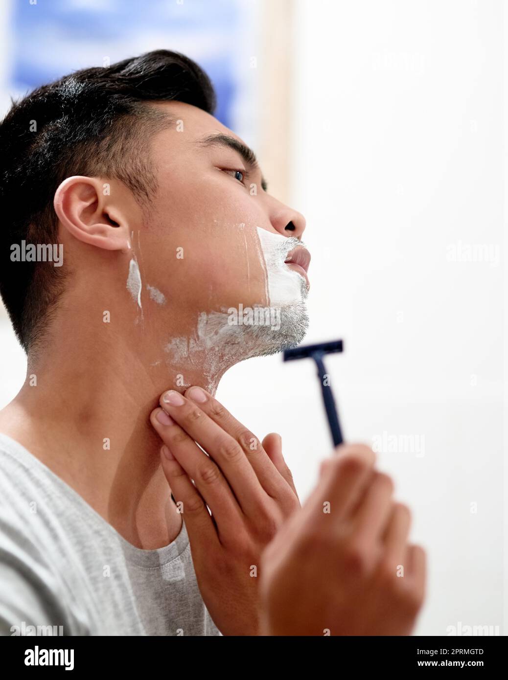 Eine gründliche Rasur. Ein ernsthafter junger Mann, der sich zu Hause den Bart rasieren kann. Stockfoto