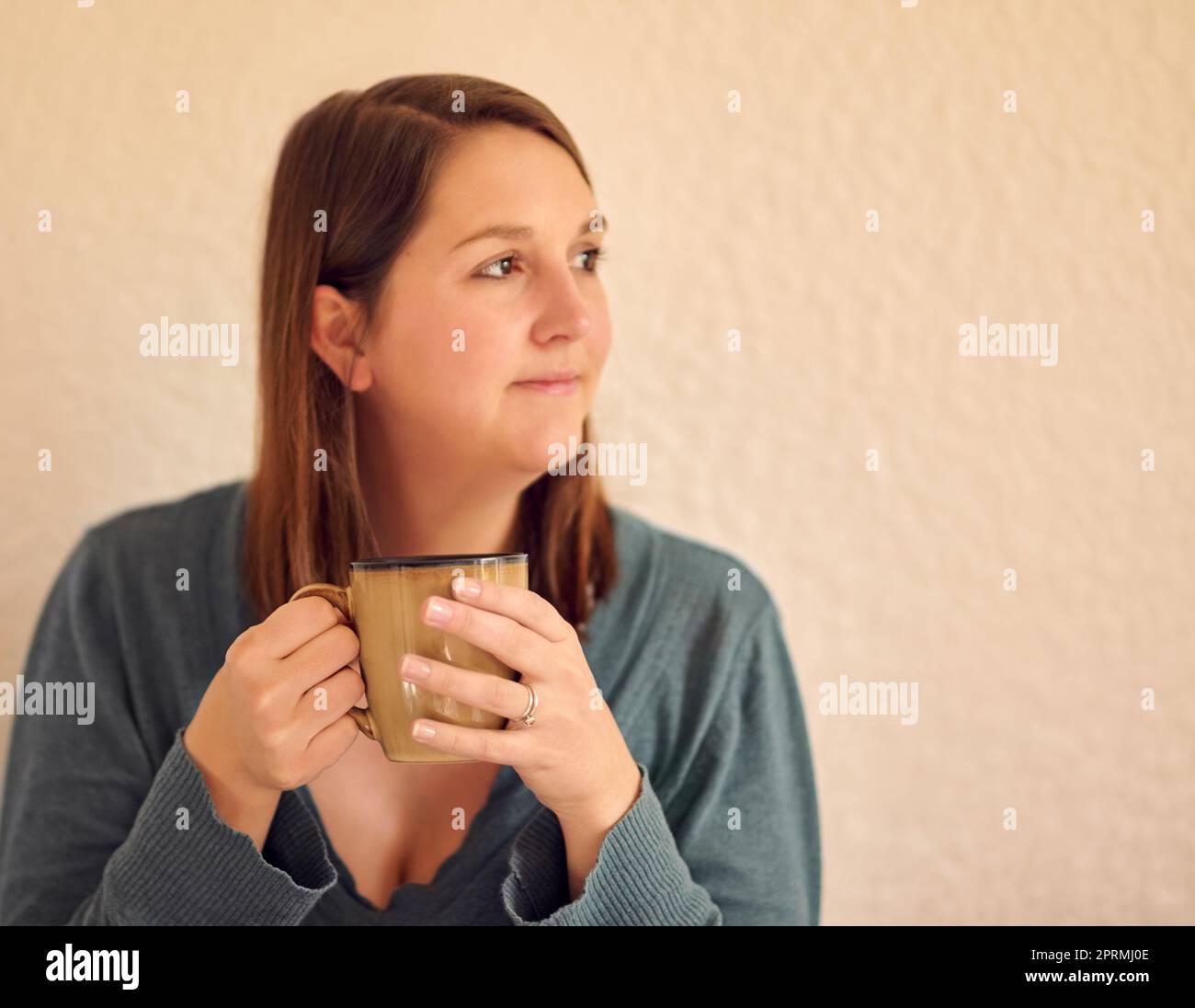 Oh, schau, seine Kaffee-Uhr. Eine entspannte junge Frau, die zu Hause eine Tasse Kaffee trinkt. Stockfoto