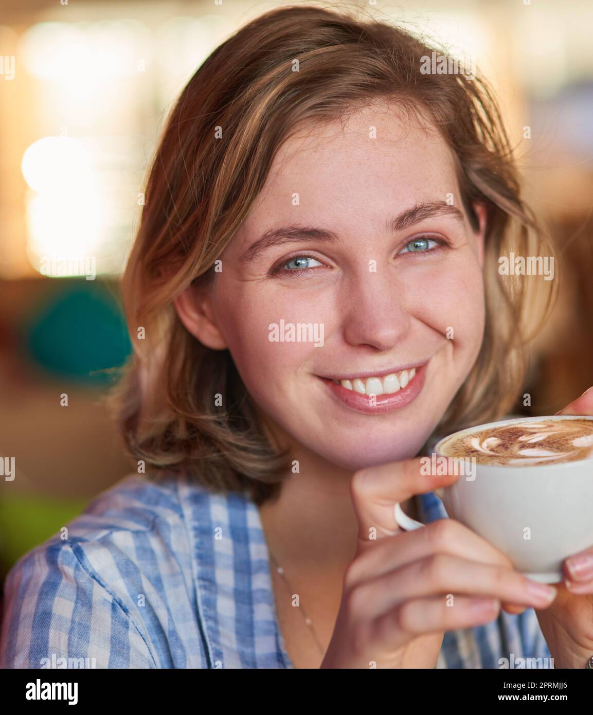 Hausgemachte Cappuccinos schmecken einfach besser. Eine glückliche junge Frau trinkt zu Hause einen Cappuccino. Stockfoto