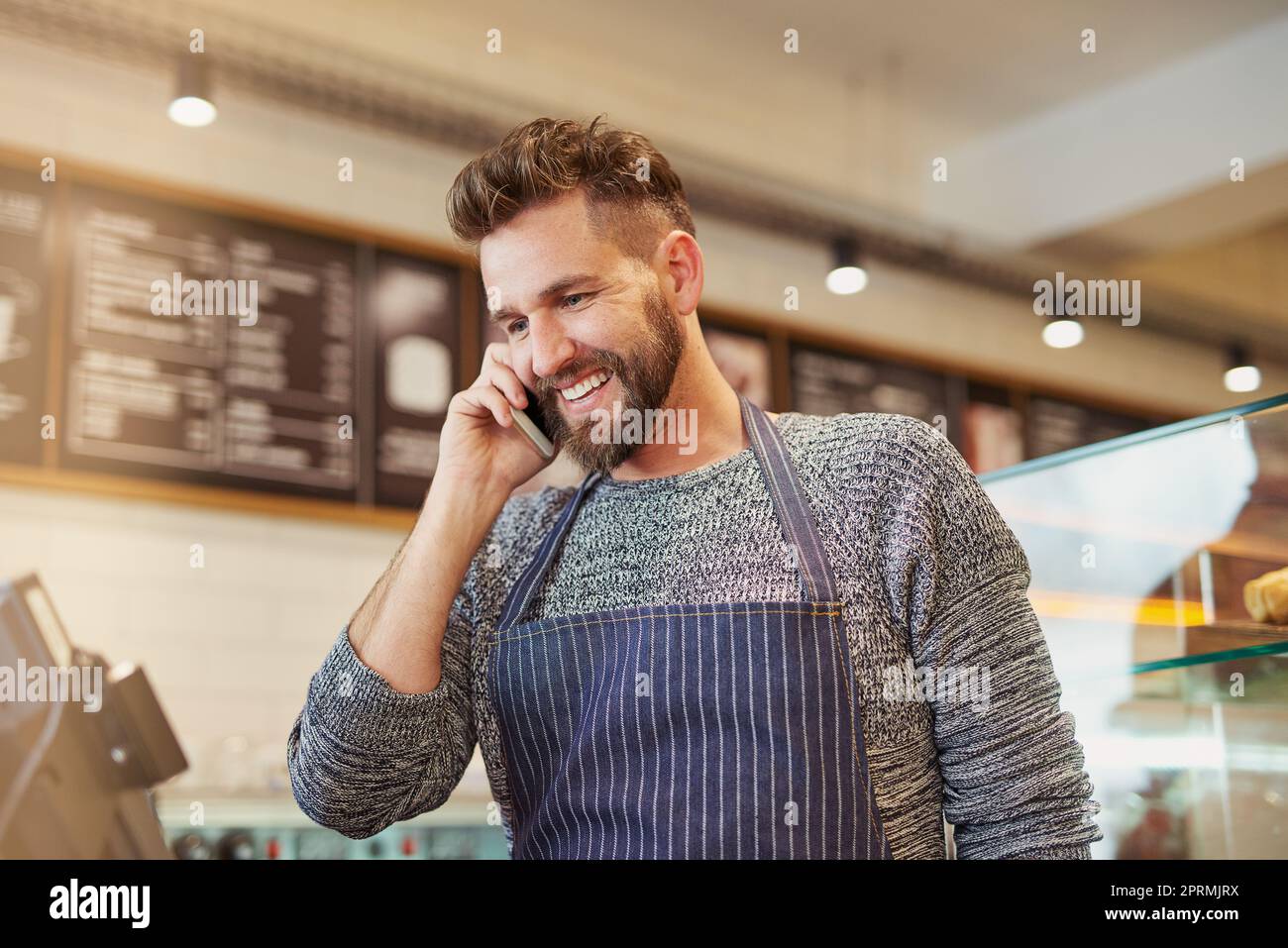 Ja, Ihre Bestellung ist bereit für die Abholung. Ein Unternehmer im Gespräch auf einem Handy in seinem Café. Stockfoto