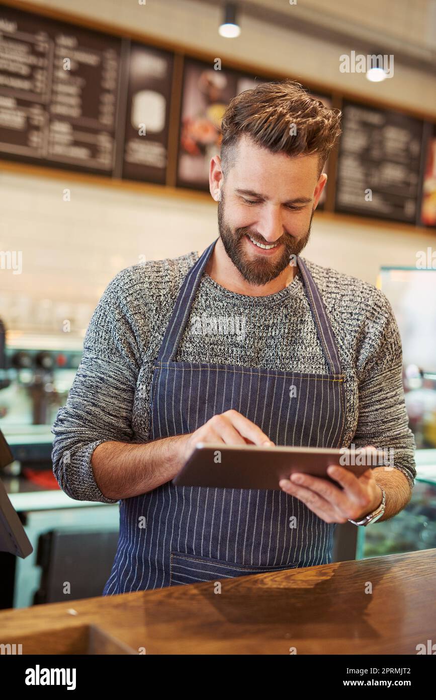 Antworten auf Kommentare von Kunden in seinen sozialen Medien. Ein Unternehmer, der ein digitales Tablet in seinem Café verwendet. Stockfoto