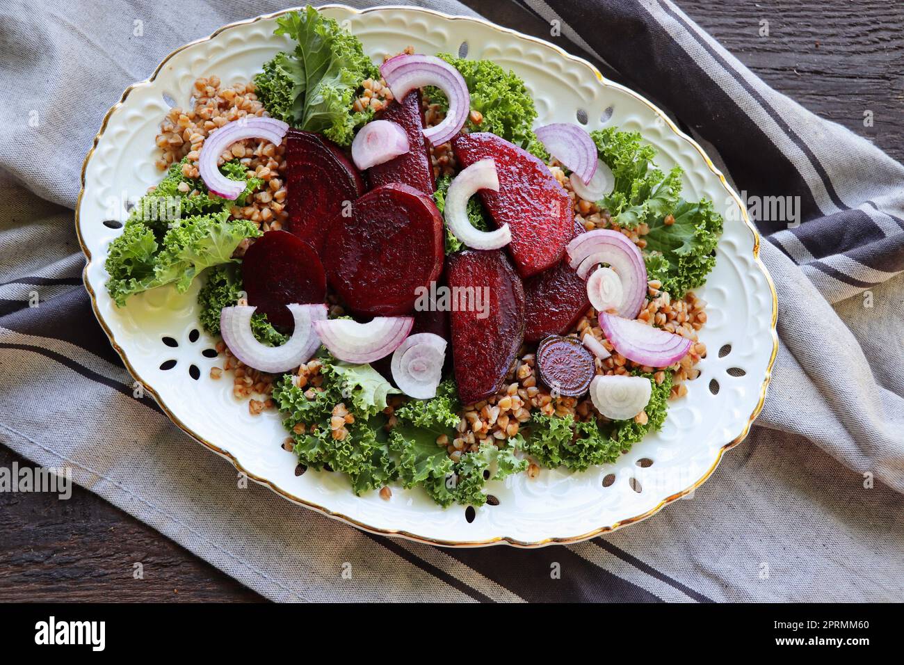 Warmer Buchweizen- und Rote-Bete-Salat auf Holzhintergrund. Vegetarische Diätidee und Rezept - Salat mit Rote Bete, Buchweizen, Grünkohl, Zwiebeln, frischen Kräutern. Draufsicht oder flach liegend Stockfoto