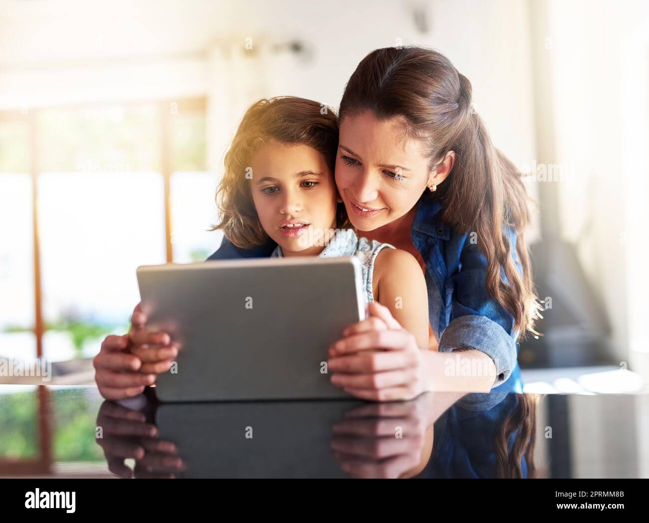 Die Wunder des World Wide Web. Eine Mutter und Tochter, die zu Hause ein digitales Tablet benutzen. Stockfoto