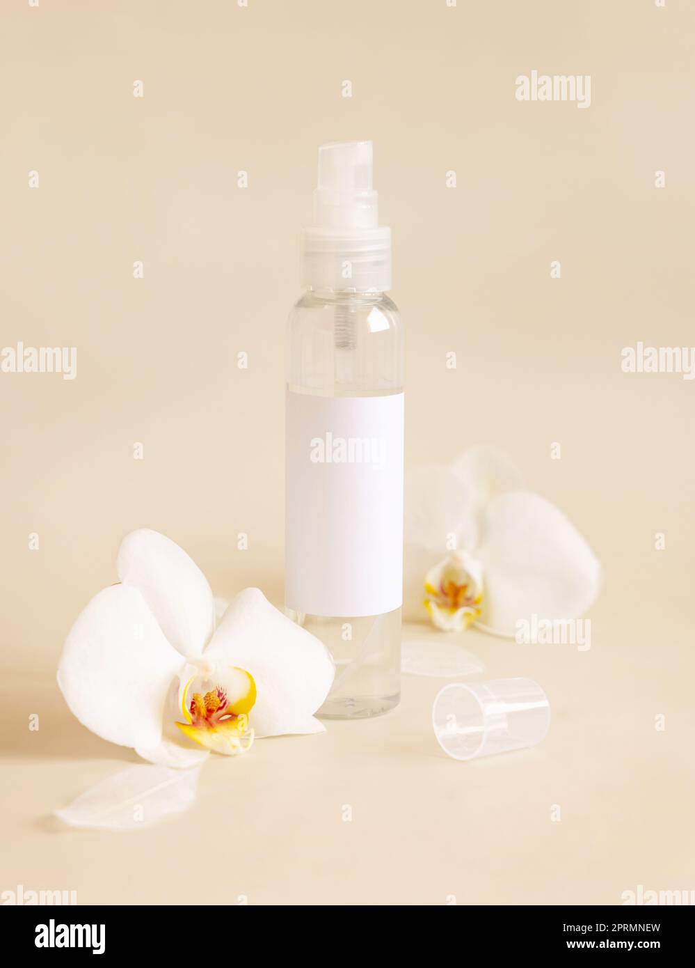 Spenderflasche neben weißen Orchideenblumen auf hellbeige Nahaufnahme. Modell Stockfoto