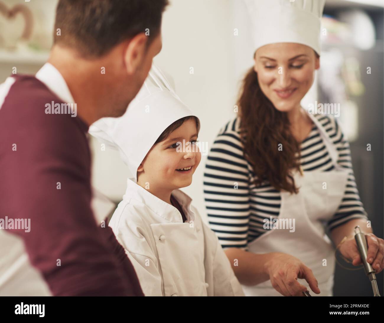 Seine Backkünste kommen gut voran. Eine lächelnde Familie, die in der Küche zusammen backt. Stockfoto