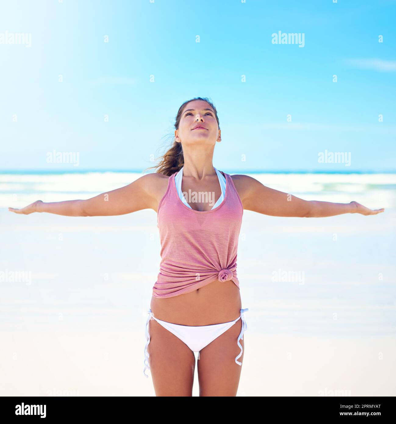 Yoga synchronisiert Geist, Körper und Seele. Eine junge Frau, die am Strand Yoga macht. Stockfoto
