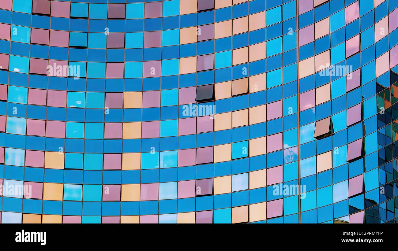 Die Glasfassade eines modernen Gebäudes. Mehrfarbige Reflexionen in den Fenstern. Quadrate und Linien. Geometrisches abstraktes Hintergrundbild Stockfoto