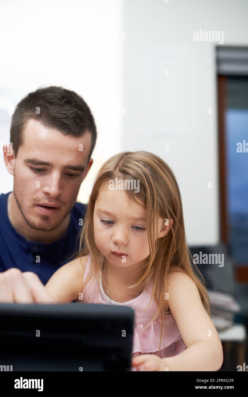 Teilen Sie ihr die Wunder der Technologie mit. Ein Vater lehrt seine Tochter, wie man Technologie nutzt. Stockfoto