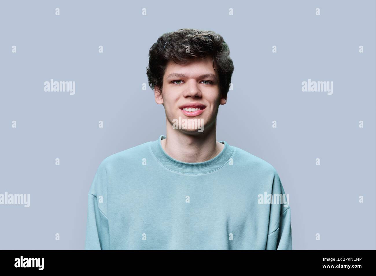 Porträt eines jungen Mannes in legerem Sweatshirt auf grauem Hintergrund Stockfoto