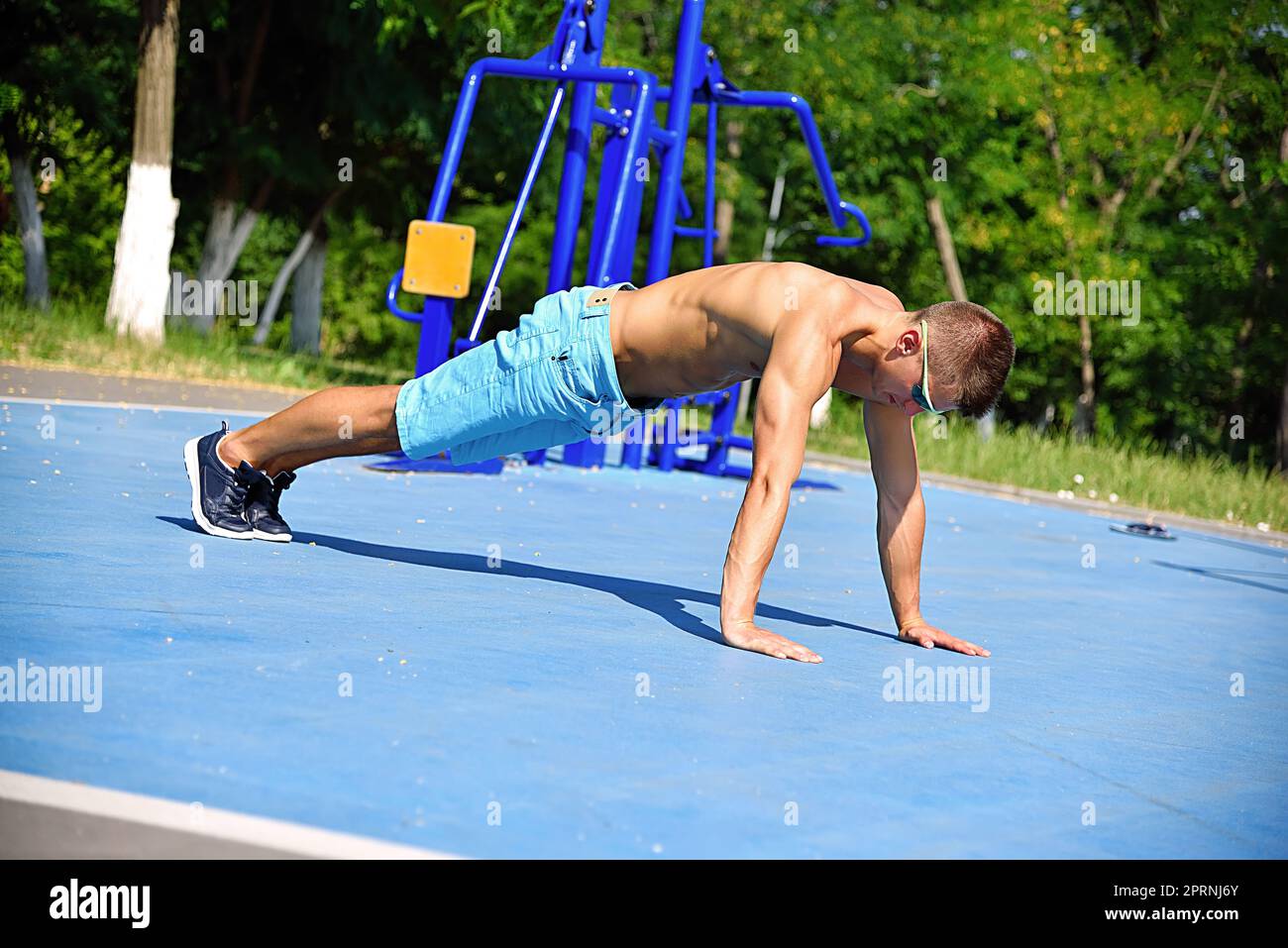 Muskulöser Mann beim Liegestützen auf dem Spielplatz im Freien. Crossfit-Konzept Stockfoto