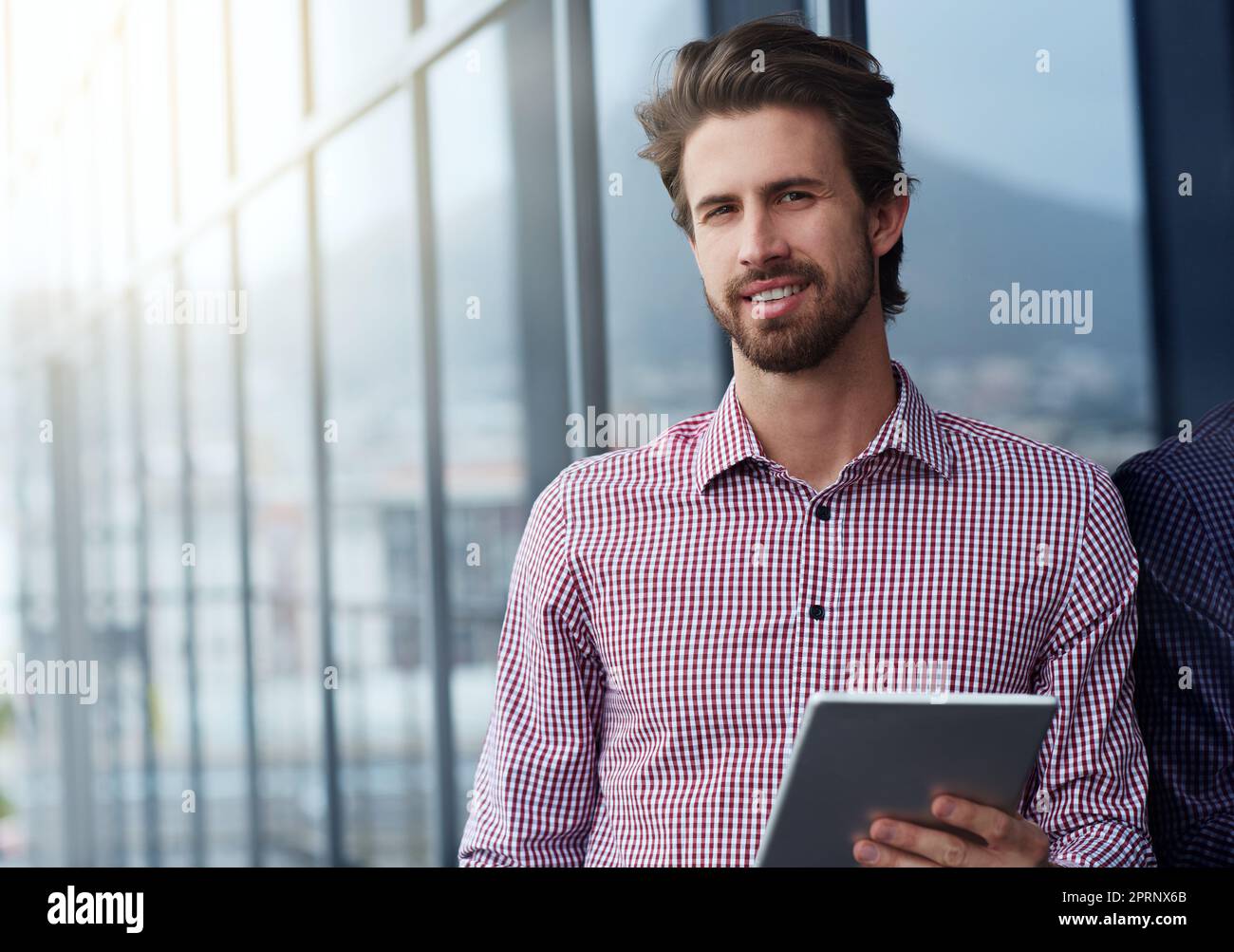 Mein Tablet ist ein tragbarer Schreibtisch. Porträt eines jungen Geschäftsmannes, der ein digitales Tablet vor einem Bürogebäude benutzt. Stockfoto