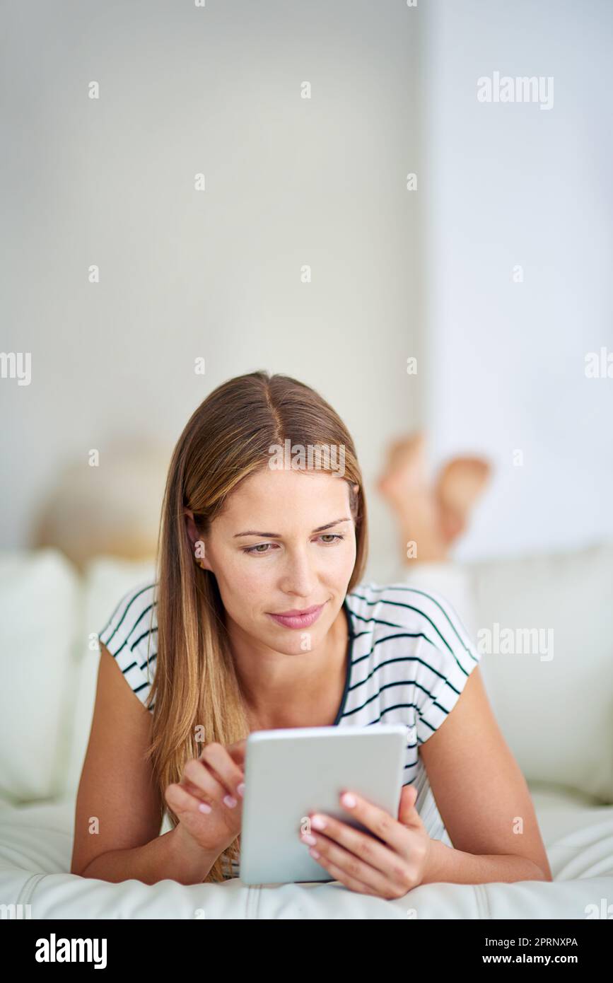 Surfen von einer bequemen Couch aus. Eine junge Frau, die zu Hause im Internet surft. Stockfoto