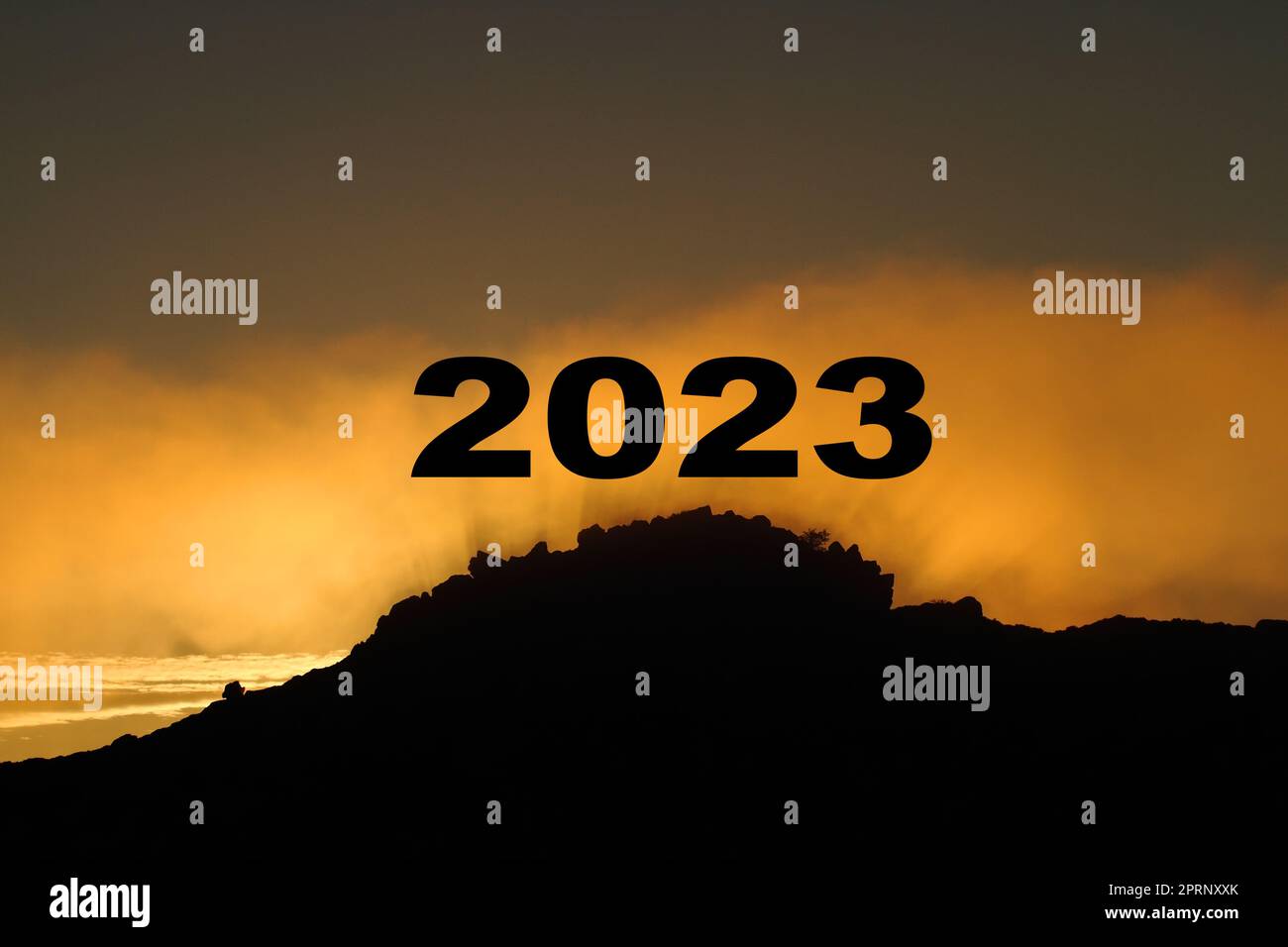Frohes neues Jahr 2023 mit großen Silhouettenbuchstaben auf dem Berg mit wunderschönem Sonnenlicht, goldenem Himmel und Wolken für ein erfolgreiches Konzept Stockfoto