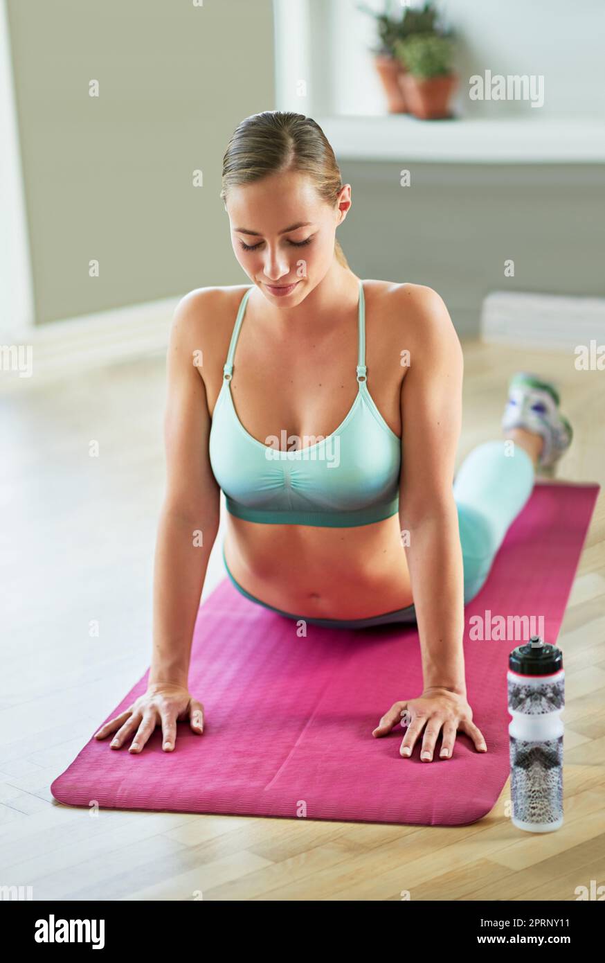 Beginn ihrer Yoga-Routine. Eine attraktive junge Frau, die zu Hause Yoga macht. Stockfoto