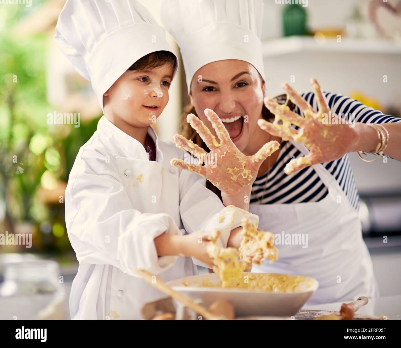 Setzen Sie den Spaß in das Backen. Eine Mutter und ihr Sohn spielen mit Plätzchenteig in der Küche. Stockfoto
