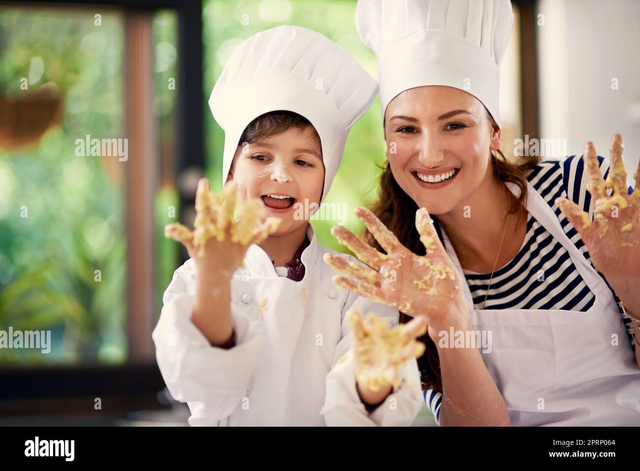 Genießen Sie die Kochzeit. Eine Mutter und ihr Sohn spielen mit Plätzchenteig in der Küche. Stockfoto