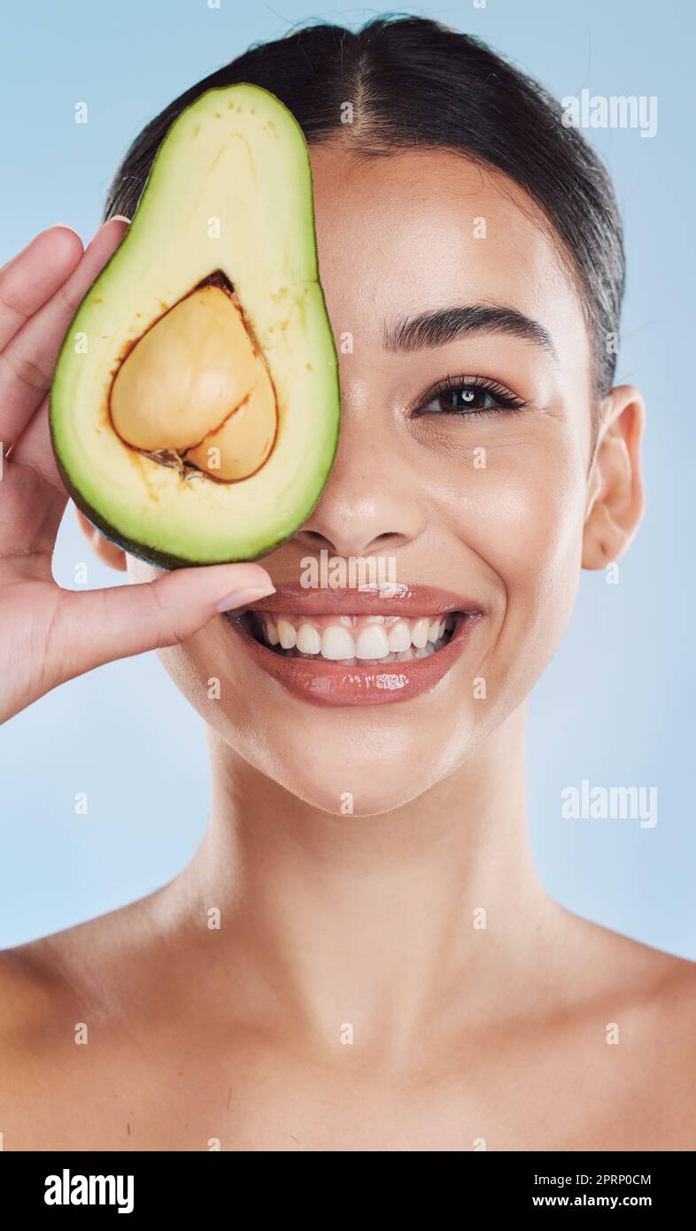 Avocado-, Wellness- und Hautpflege-Frau Porträt auf blauem Studiohintergrund und Modell. Junges Modell mit natürlicher Bio-Ernährung für Gesicht und Gesundheit mit grünem, sauberem und gesundem Lebensstil Stockfoto